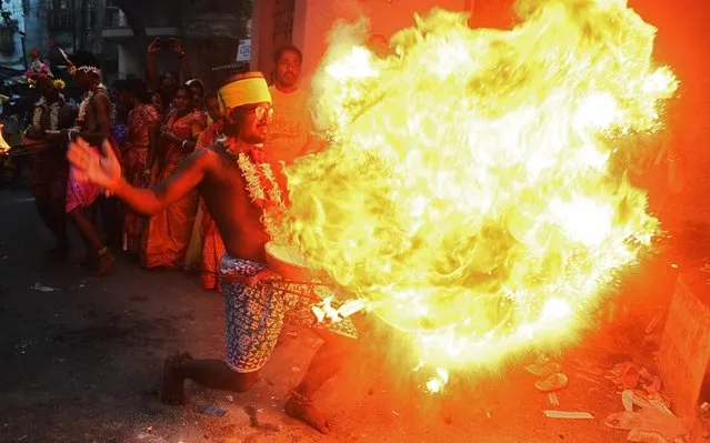 Hindu devotees throw holy flammable powder onto a fire as they perform rituals during Gajan Festival celebrations in Kolkata on April 13, 2019. The Gajan festival falls on the last day of the Bengali calendar which also coincides with the birth of Lord Shiva, according to Hindu mythology. (Photo by Dibyangshu Sarkar/AFP Photo)
