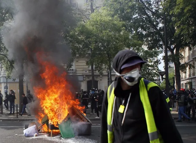 A man walks past garbage that was put on fire in Paris, Wednesday, May 1, 2019. Brief scuffles between police and protesters have broken out in Paris as thousands of people gather for May Day rallies under tight security measures. (Photo by Francois Mori/AP Photo)