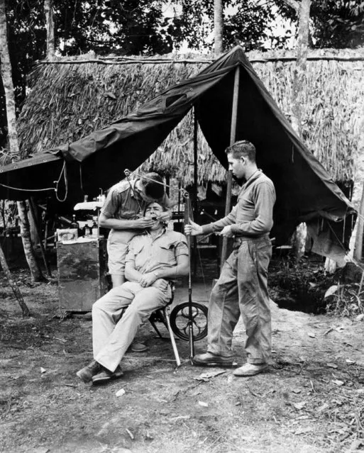 First Lt. (Dentist) W.A. Reiter of Meltcher, Iowa, works on a tooth of Cpl. Cloyd Reese of Kemmerer, Wyoming. Pvt. Roger Cram of Medford, Ore., operates the foot treadle for the drill somewhere in New Guinea on June 8, 1943. (Photo by AP Photo)