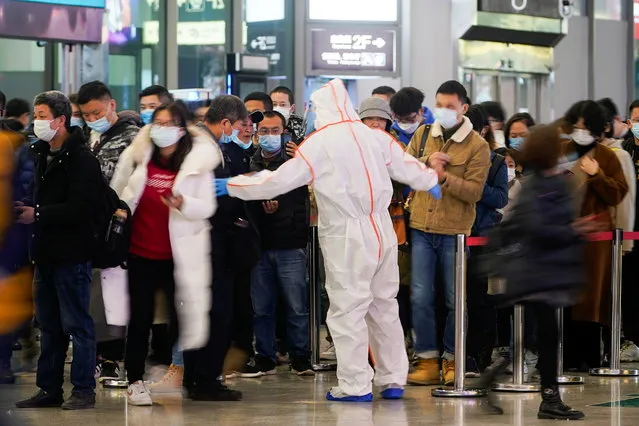 A security guard blocks an exit as he directs people to scan a QR code to track their health status at Shanghai Hongqiao Railway Station, following new cases of the coronavirus disease (COVID-19), in Shanghai, China, November 25, 2021. (Photo by Aly Song/Reuters)