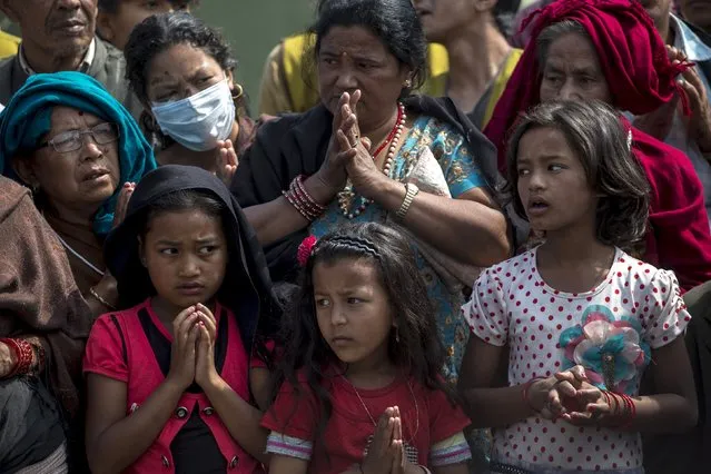 Local residents pray as they queue up for relief supplies distributed by international aid organisation after the April 25 earthquake in Bhaktapur, Nepal, May 10, 2015. (Photo by Athit Perawongmetha/Reuters)