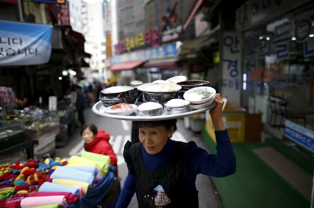 A restaurant worker carries a plate on her head as she delivers a food during a lunch time at the Namdaemun Market in Seoul, South Korea, November 24, 2015. (Photo by Kim Hong-Ji/Reuters)