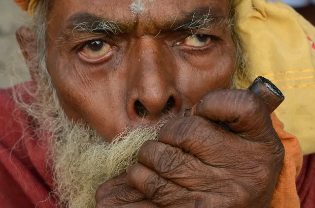 A Nepalese Sadhu (Hindu holy man) smokes a traditional clay pipe chillum as a holy offering to Lord Shiva, the Hindu god of creation and destruction, near the Pashupatinath Temple in Kathmandu on February 23, 2017, on the eve of the Hindu festival Maha Shivaratri. Hindus mark the Maha Shivratri festival by offering special prayers and fasting. (Photo by Prakash Mathema/AFP Photo)