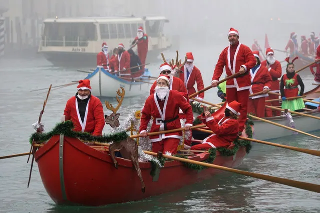 Rowers dressed as Santa Clauses lead typical boats of the lagoon while parading along the Grand Canal in Venice, Italy, 19 December 2021. (Photo by Andrea Merola/EPA/EFE)