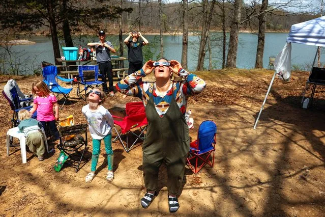 Brittany Sunderman from Effingham, Illinois and members of the Debenham family who traveled from Utah, Las Vegas, and Illinois to experience the total solar eclipse together, try out their eclipse viewing glasses at their campsite a day ahead of the event, at Camp Carew in Makanda, Illinois on April 8, 2024. (Photo by Evelyn Hockstein/Reuters)