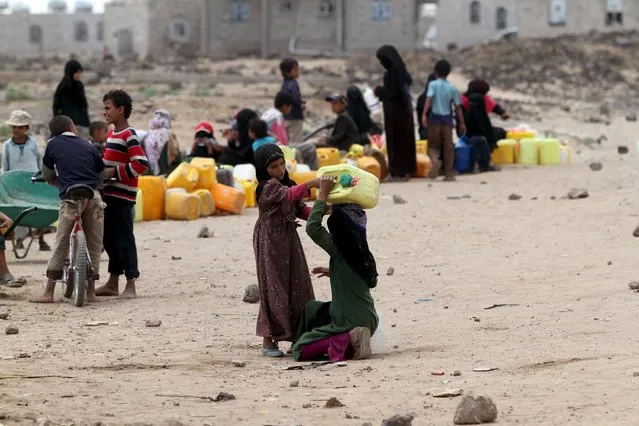 A girl helps her sister to carry a jerrycan filled with water from a public tap amidst an acute water shortage in Sanaa May 13, 2015. (Photo by Mohamed al-Sayaghi/Reuters)