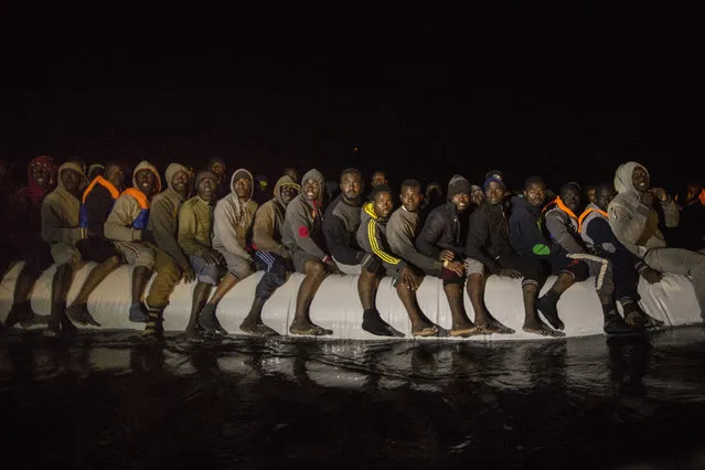 Refugees and migrants from many different African nationalities sit aboard an overcrowded rubber boat leaving Libyan territorial waters early Sunday, March 5, 2017. The Spanish NGO Proactiva Open Arms found the boat after a long search coordinated with Italian authorities and took everyone aboard it's ship. (Photo by Santi Palacios/AP Photo)