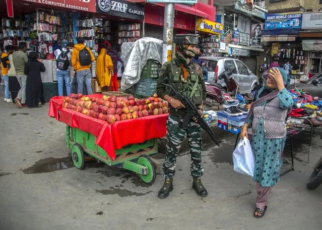 An Indian paramilitary soldier guards as a Kashmiri woman walks at a busy market in Srinagar, Indian controlled Kashmir, Monday, October 11, 2021. The government forces have beefed up security in the region’s main city following a string of targeted killings last week. (Photo by Mukhtar Khan/AP Photo)