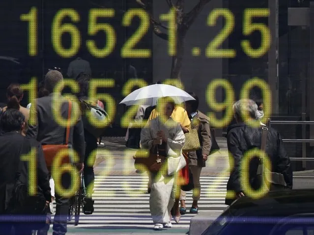A woman clad in a kimono is reflected in an electronic board displaying Japan's Nikkei share average outside a brokerage in Tokyo, Japan, April 18, 2016. Tumbling crude oil futures knocked Asian shares on Monday after producers' weekend talks failed to agree a plan to curb the global supply glut, while Tokyo stocks slumped as investors assessed the impact of a devastating earthquake in southwestern Japan. (Photo by Toru Hanai/Reuters)