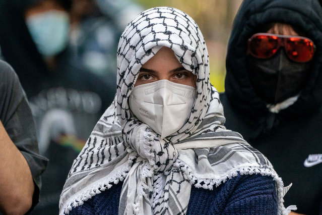 A demonstrator wears a protective mask as protestors gather at the gates of Columbia University, in support of student protesters who barricaded themselves in Hamilton Hall, despite orders from university officials to disband or face suspension, during the ongoing conflict between Israel and the Palestinian Islamist group Hamas, in New York City, U.S., April 30, 2024. (Photo by David Dee Delgado/Reuters)