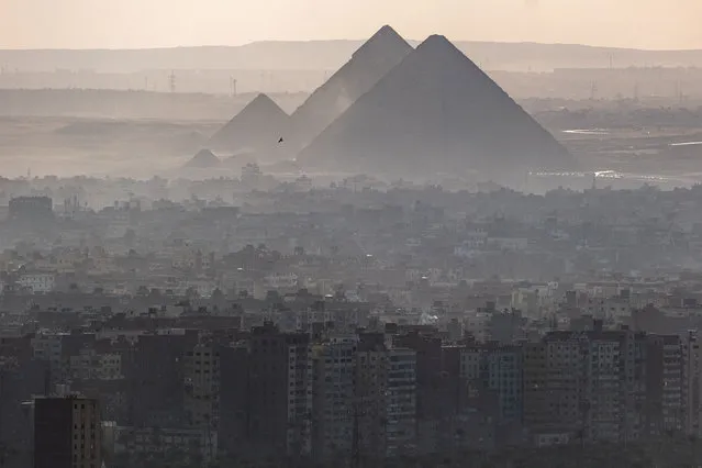 A bird flies in the sky before the Giza pyramids necropolis in the Egyptian capital's twin city of Giza on January 13, 2022. (Photo by Amir Makar/AFP Photo)