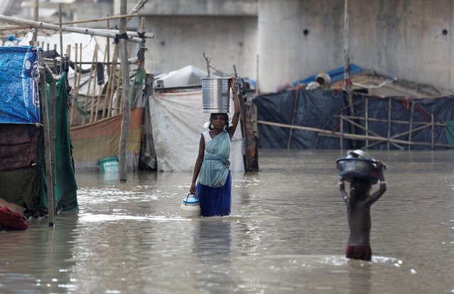 Girls carrying their belongings wade through a flooded area of a slum on the banks of the river Yamuna in Delhi, India, August 20, 2019. (Photo by Anushree Fadnavis/Reuters)