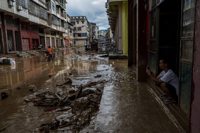 This photo taken on June 18, 2024 shows a man squatting on a muddy street in the aftermath of flooding from heavy storms in Meizhou, in southern China's Guangdong province. (Photo by AFP Photo/China Stringer Network)
