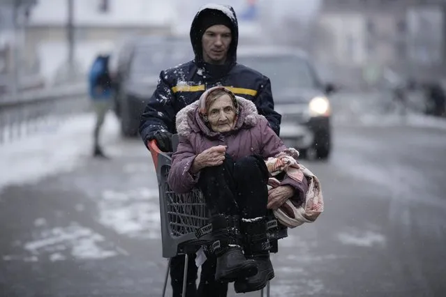 An elderly lady is carried in a shopping cart after being evacuated from Irpin, on the outskirts of Kyiv, Ukraine, Tuesday, March 8, 2022. Demands for ways to safety evacuate civilians have surged along with intensifying shelling by Russian forces, who have made significant advances in southern Ukraine but stalled in some other regions. Efforts to put in place cease-fires along humanitarian corridors have repeatedly failed amid Russian shelling. (Photo by Vadim Ghirda/AP Photo)