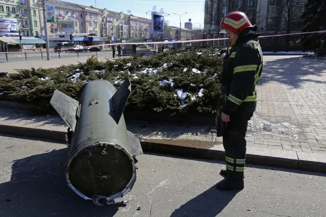 A firefighter looks at a fragment of a Ukrainian Tochka-U missile on a street in Donetsk in eastern Ukraine, Monday, March 14, 2022. The Russian military says that at least 20 civilians have been killed by a ballistic missile launched by the Ukrainian forces. (Photo by Alexei Alexandrov/AP Photo)