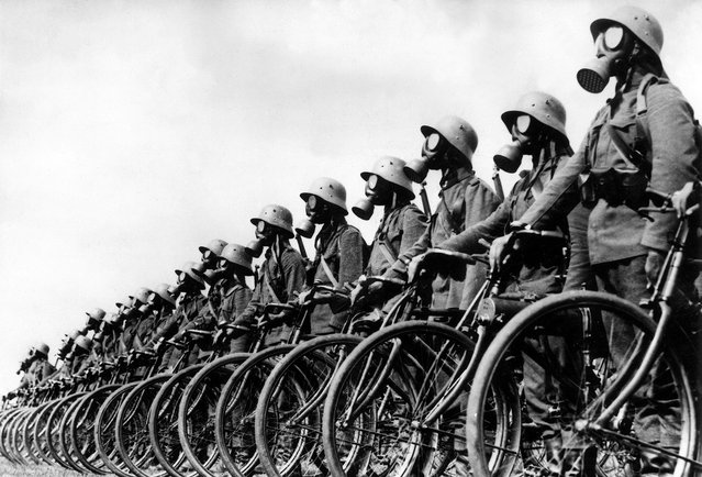 circa 1939:  Full-length view of members of the German light machine-gun Cyclist Corps wearing gas masks while standing next to their bicycles in a lineup in Austria during World War II. A machine gun is attached to one of the bicycles (2nd from R).  (Photo by Hulton Archive/Getty Images)