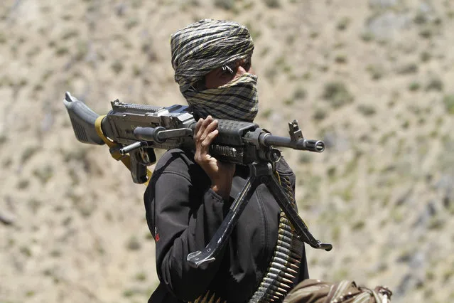 In this Friday, May 27, 2016 photo, a member of a breakaway faction of the Taliban fighters guards a gathering in Shindand district of Herat province, Afghanistan. In the rugged terrain of the Taliban heartland in southern Afghanistan, the fight against Kabul has become a war for control of key stretches of main roads and highways as the insurgents use a new tactic to gain ground. (Photo by Allauddin Khan/AP Photos)