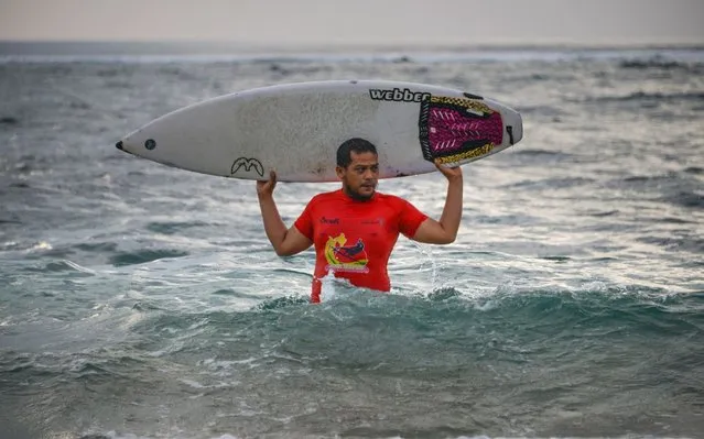 This picture taken on December 9, 2019 shows Dery Setyawan, a survivor of the December 26, 2004 tsunami, holdinghis surfboard after surfing on Lhoknga beach in Banda Aceh, Aceh province. On December 26, 2004, a monstrous 9.3 magnitude quake struck undersea off the coast of Sumatra. It sparked a tsunami nearly 100 feet (30 meters) high that killed more than 220,000 across a string of Indian Ocean countries, including Thailand, Sri Lanka and India. (Photo by Chaideer Mahyuddin/AFP Photo)
