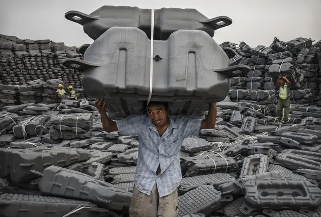 A Chinese worker carries flotation devices used to support panels to be used in a large floating solar farm project under construction by the Sungrow Power Supply Company on a lake caused by a collapsed and flooded coal mine on June 12, 2017 in Huainan,  Anhui province, China. The floating solar field, billed as the largest in the world, is built on a part of the collapsed Panji No.1 coal mine that flooded over a decade ago due to over-mining, a common occurence in deep-well mining in China's coal heartland. When finished, the solar farm will be made up of more than 166,000 solar panels which convert sunlight to energy, and the site could potentially produce enough energy to power a city in Anhui province, regarded as one of the country's coal centers. Local officials say they are planning more projects like it, marking a significant shift in an area where long-term intensive coal mining has led to large areas of subsidence and environmental degradation. However, the energy transition has its challenges, primarily competitive pressure from the deeply-established coal industry that has at times led to delays in connecting solar projects to the state grid. China's government says it will spend over US $360 billion on clean energy projects by 2020 to help shift the country away from a dependence on fossil fuels, and earlier this year, Beijing canceled plans to build more than 100 coal-fired plants in a bid to ease overcapacity and limit carbon emissions. Already, China is the leading producer of solar energy, but it also remains the planet's top emitter of greenhouse gases and accounts for about half of the world's total coal consumption. (Photo by Kevin Frayer/Getty Images)