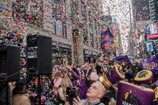 People watch confetti as it's thrown from the Hard Rock Cafe marquee as part of the annual confetti test ahead of the New Year's Eve ball-drop celebrations in Times Square in New York City, New York, U.S., December 29, 2019. (Photo by Jeenah Moon/Reuters)