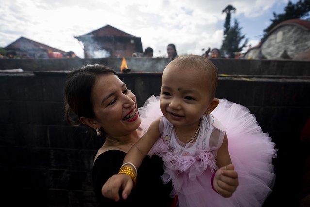 A woman plays with her child at the Pashupatinath temple during Teej festival celebrations in Kathmandu, Nepal, Friday, September 6, 2024. (Photo by Niranjan Shrestha/AP Photo)