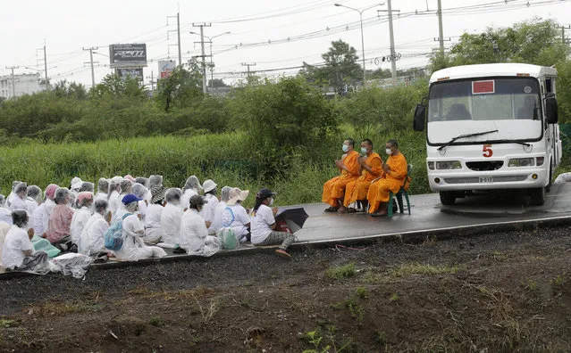 Buddhist monks and devotees pray and block a road outside the Wat Phra Dhammakaya temple in Pathum Thani province, north of Bangkok, Thailand, Thursday, June 16, 2016. Police entered the sprawling Buddhist temple complex after wading through thousands of devotees camped on the grounds to arrest a popular abbot accused of embezzling $14 million. (Photo by Sakchai Lalit/AP Photo)