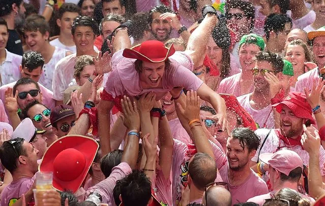 A reveller is tossed by other participants as they celebrate the “Chupinazo” (start rocket) to mark the kickoff at noon sharp of the San Fermin Festival, in front of the Town Hall of Pamplona, northern Spain, on July 6, 2017. A red-and-white sea of revelers soaked each other with wine in a packed Pamplona square today to kick off Spain's most famous fiesta, the San Fermin bull-running festival. (Photo by Miguel Riopa/AFP Photo)