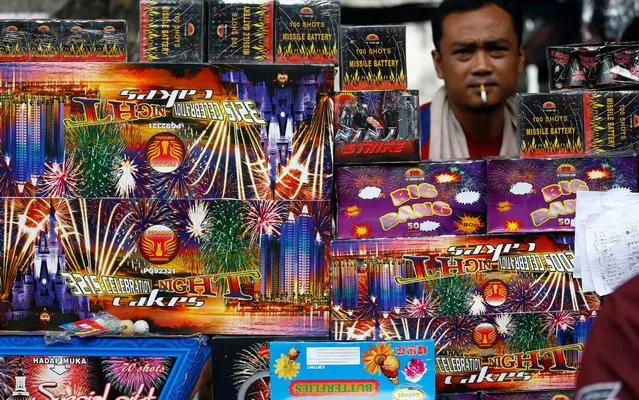 A vendor selling fireworks smokes a cigarette as he waits for customers at a market in Jakarta, Indonesia, December 31, 2019. (Photo by Ajeng Dinar Ulfiana/Reuters)