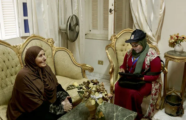 In this May 24, 2017 photo, a Central Agency for Public Mobilization and Statistics worker looks at the identification card of an elderly woman as she fills them into the tablet at her home, in the Omraniyah district of Cairo, Egypt. Census workers going door to door in Egypt’s teeming neighborhoods and crowded towns are discovering a new country – of more than 20 million people born in the last decade alone. (Photo by Nariman El-Mofty/AP Photo)