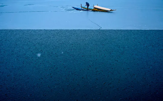 A man rides a boat in the Dal Lake during a snowfall in Srinagar on January 13, 2020. (Photo by Tauseef Mustafa/AFP Photo)