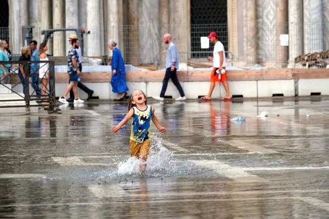 A child plays in a flooded St. Mark's Square during high tide as the flood barriers known as MOSE are not raised, in Venice, Italy on June 24, 2022. (Photo by Manuel Silvestri/Reuters)