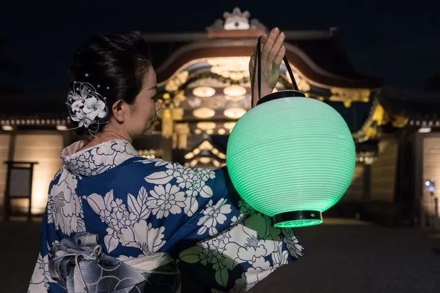 A guest attendee holding a lantern  poses for her social media during a preview of the Naked Summer Festival 2022 at Nijo-jo Castle on July 21, 2022 in Kyoto, Japan. The exhibition will make use of projection mapping and virtual events in the metaverse to display art at the UNESCO-listed historic castle from July 22 to Aug. 21. (Photo by Tomohiro Ohsumi/Getty Images)
