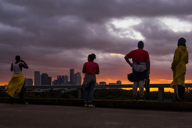 People stand on Hirsch Road to watch the sun sets over the Houston skyline as Tropical Storm Harvey moves out of the region Tuesday, August 29, 2017. (Photo by Michael Ciaglo/Houston Chronicle via AP Photo)