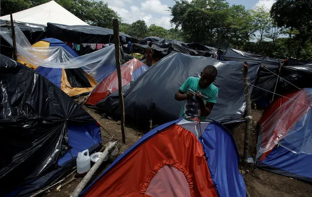 An African migrant stranded in Costa Rica, repairs his tent at makeshift camp at the border between Costa Rica and Nicaragua, in Penas Blancas, Costa Rica, July 14, 2016. (Photo by Juan Carlos Ulate/Reuters)