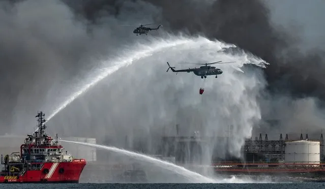The Mexican firefighting vessel “Bourbon Artabaze” and helicopters battle to contain the days-old blaze at a fuel depot sparked by a lightning strike in Matanzas, Cuba, on August 10, 2022. The massive fire, which started on Friday, has destroyed four tanks and was threatening four more and left a 60-year-old firefighter dead and 14 colleagues missing, according to authorities. More than 100 people were reported injured, with 22 still hospitalized. (Photo by Yamil Lage/AFP Photo)