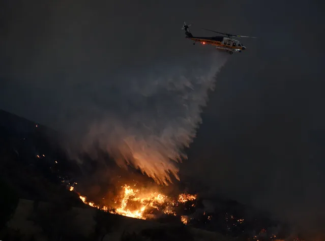 A firefighting helicopter makes a drop at Fair Oaks Canyon as they battle a blaze dubbed the “Sand Fire” in Santa Clarita, California on July 24, 2016. A fire burning out of control in Southern California has grown to a massive 20,000 acres, officials said on July 24, as residents in an area north of Los Angeles were forced to evacuate. (Photo by Mark Ralston/AFP Photo)