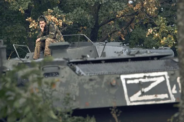 A Ukrainian soldier sits atop a Russian armoured personnel carrier in Izium, Kharkiv region, Ukraine, Tuesday, September 13, 2022. Ukrainian troops piled pressure on retreating Russian forces Tuesday, pressing deeper into occupied territory and sending more Kremlin troops fleeing ahead of the counteroffensive that has inflicted a stunning blow on Moscow's military prestige. (Photo by Kostiantyn Liberov/AP Photo)