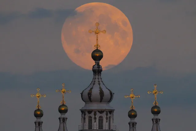 The full moon is seen rising in the sky above the domes of the Smolny Cathedral in St. Petersburg, Russia, Monday, September 8, 2014. Monday night's full moon, also known as a Harvest Moon, will be the third and final “supermoon” of 2014. The phenomenon, which scientists call a “perigee moon”, occurs when the moon is near the horizon and appears larger and brighter than other full moons. (Photo by Dmitry Lovetsky/AP Photo)