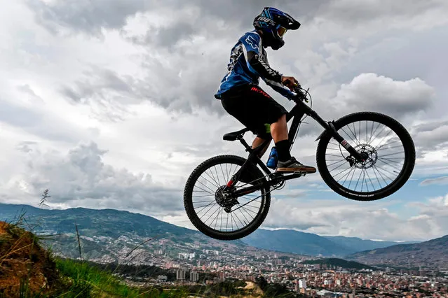 A man jumps on a downhill bike at the Three Crosses hill in Medellin, Colombia, on May 3, 2020, amid the new coronavirus pandemic. Colombia extended mandatory preventive isolation due to COVID-19 until at least May 11, however, in the city of Medellin people are allowed to excercise outdoors one hour a day (Photo by Joaquín Sarmiento/AFP Photo)