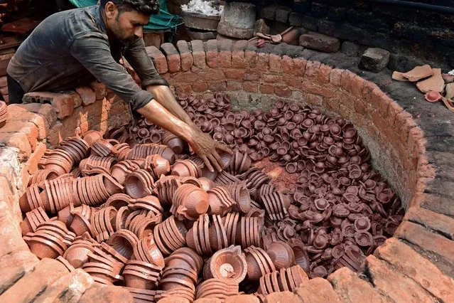 A potter arranges traditional earthen oil lamps in an oven at a workshop ahead of the Navratri festival on the outskirts of Ahmedabad on September 11, 2022. (Photo by Sam Panthaky/AFP Photo)