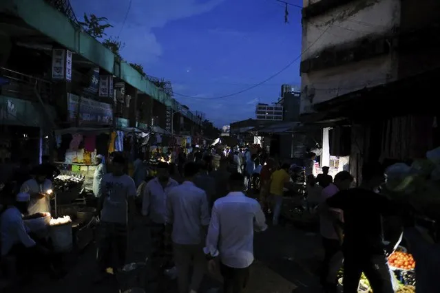 People walk through a dark street after a failure in Bangladesh's national power grid plunged much of the country into a blackout in Dhaka, Bangladesh, Tuesday, October 4, 2022. (Photo by Mahmud Hossain Opu/AP Photo)