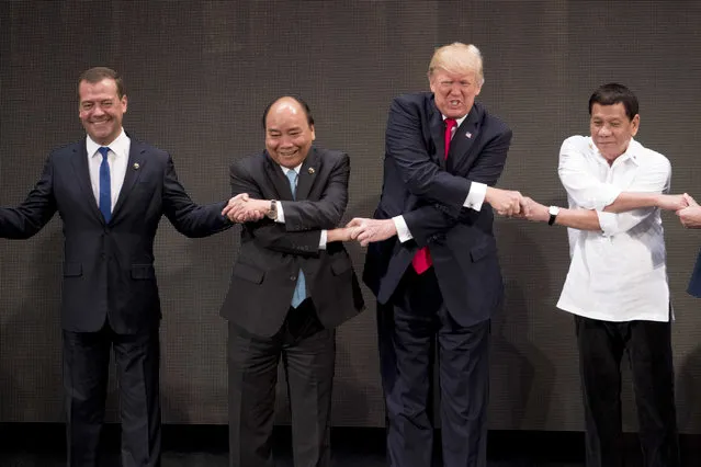 U.S. President Donald Trump, second from rigtht, reacts as he does the “ASEAN-way handshake” with Russian Prime Minister Dmitry Medvedev, left, Vietnamese President Tran Dai Quang, second from left, and Philippine President Rodrigo Duterte on stage during the opening ceremony at the ASEAN Summit at the Cultural Center of the Philippines, Monday, November 13, 2017, in Manila, Philippines. Trump initially did the handshake incorrectly. Trump is on a five-country trip through Asia traveling to Japan, South Korea, China, Vietnam and the Philippines. (Photo by Andrew Harnik/AP Photo)