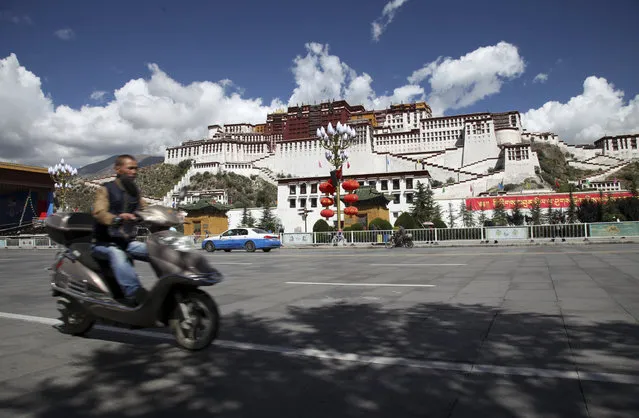 In this Friday, September 18, 2015 photo, a man on a scooter drives past the Potala Palace, the traditional seat of Tibetan political and spiritual leadership and residence of Dalai Lamas since the 17th century in Lhasa, capital of the Tibet Autonomous Region in China. The last official resident of the palace was Tenzin Gyatso, the 14th Dalai Lama, who fled to exile to India in 1959. (Photo by Aritz Parra/AP Photo)