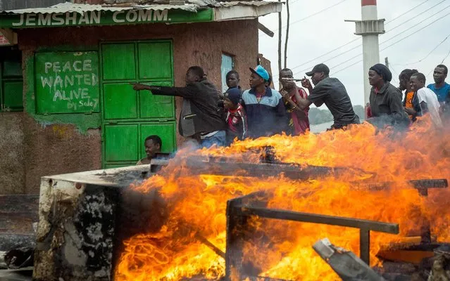 Supporters of Kenya' s opposition party National Super Alliance (NASA) take shelter behind a building next to a fire as they demonstrate in Kibera slum, in Nairobi, on November 20, 2017 after Kenya' s Supreme Court dismissed two petitions to overturn the country' s October 26 presidential election re- run, validating the poll victory of Kenyatta Kenya' s Supreme Court validated the election victory of President Uhuru Kenyatta, sparking opposition protests that left two dead, according to police. While the court decision led to celebrations in ruling party strongholds. (Photo by Georgina Goodwin/AFP Photo)