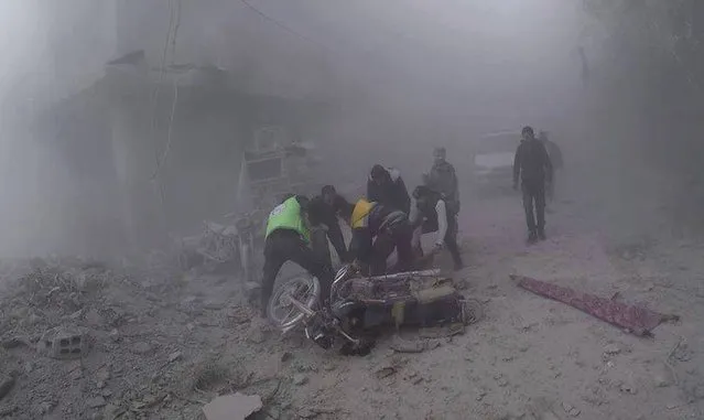 In this photo provided by the Syrian Civil Defense group in Damascus suburbs known as the White Helmets, Civil Defense workers carry an injured man after government airstrikes hit Douma, near Damascus, Syria, Sunday November 26, 2017. Government airstrikes and shelling outside the Syrian capital killed at least 22 civilians, activists reported Sunday, as the fighting showed no signs of letting up ahead of the resumption of U.N. peace talks in Geneva. (Photo by Syrian Civil Defense in Damascus suburbs via AP Photo)