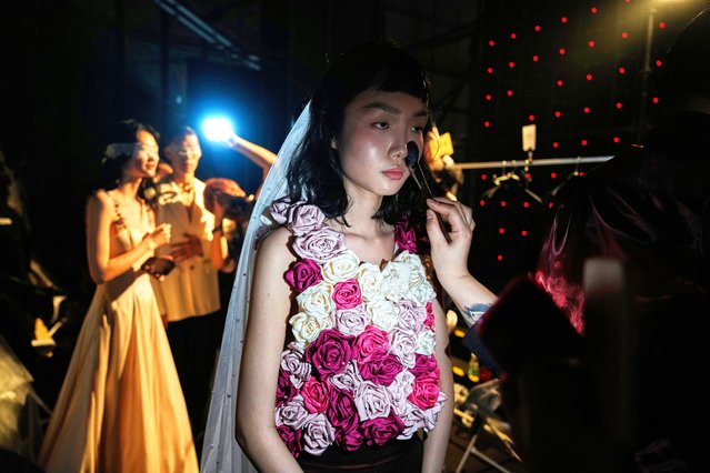 Models wearing the latest bridal design from the Huqiu Bridal City prepare backstage for a show during China Fashion Week in Beijing, Friday, March 21, 2025. (Photo by Ng Han Guan/AP Photo)