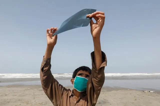 A boy holds an x-ray sheet as he observes the partial solar eclipse along Clifton beach in Karachi, Pakistan June 21, 2020. (Photo by Akhtar Soomro/Reuters)