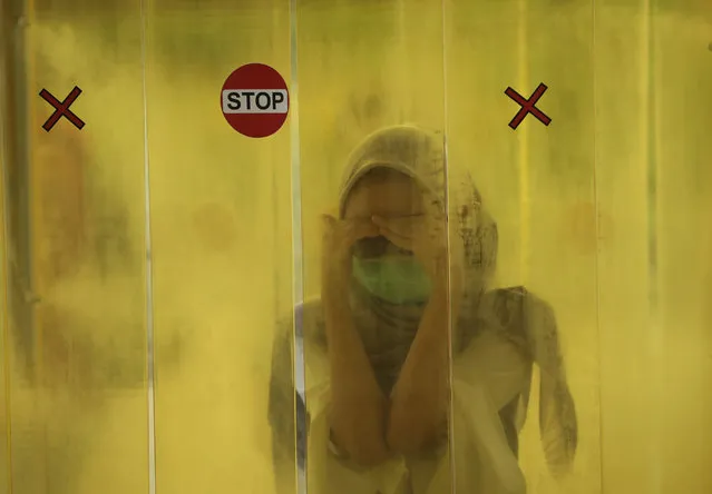 A woman reacts as she is sprayed with disinfectant inside a chamber as a precaution against the new coronavirus outbreak before entering a shopping mall in Jakarta, Indonesia, Tuesday, June 9, 2020. As Indonesia's overall virus caseload continues to rise, the capital city has moved to restore normalcy by lifting some restrictions this week, saying that the spread of the virus in the city of 11 million has slowed after peaking in mid-April. (Photo by Dita Alangkara/AP Photo)