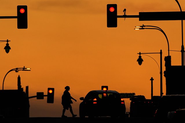 A person crosses a downtown street as the sun sets, Monday, March 31, 2025, in Kansas City, Mo. (Photo by Charlie Riedel/AP Photo)