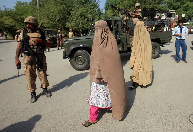 Women walk past army soldiers, who are standing guard at a street, after suicide bombers attacked a Christian neighbourhood in Khyber Agency near Peshawar, Pakistan, September 2, 2016. (Photo by Fayaz Aziz/Reuters)